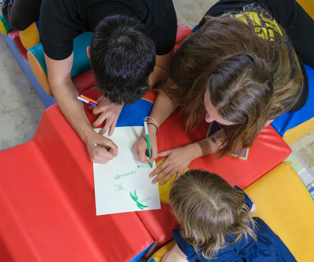 bambini disegnano stesi su materassini colorati