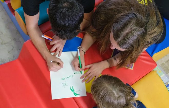 bambini disegnano stesi su materassini colorati