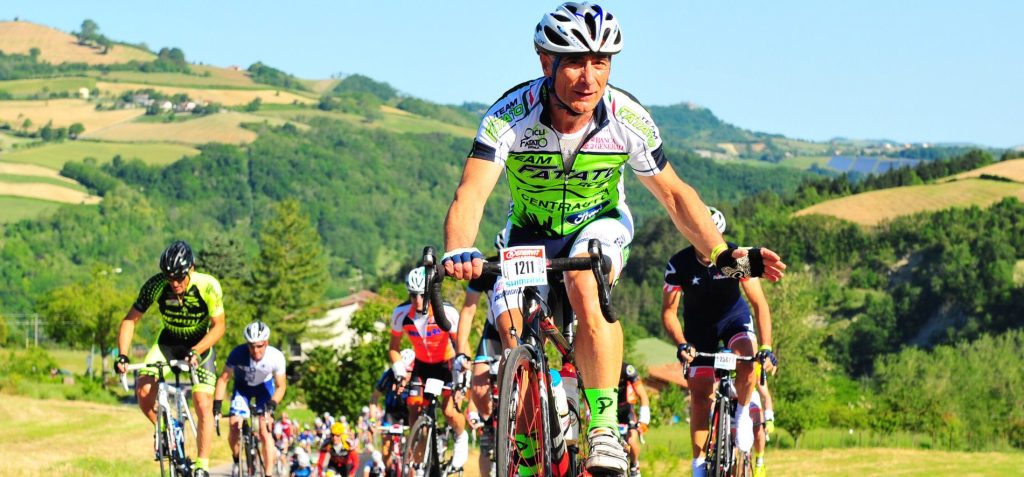 Groppo di ciclisti in strada sulle colline in una giornata di sole