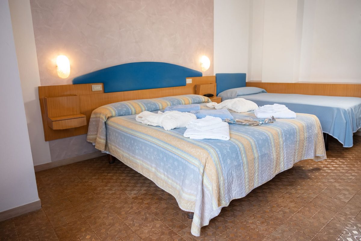 H. CAPITOL-24 camera con letto matrimoniale e letto singolo con accappatoio e asciugamani sui letti