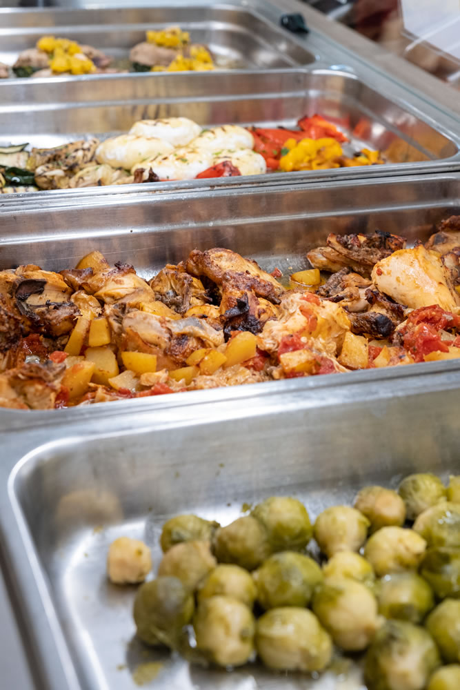 Panoramica sul buffet con pesce al forno, pollo patate e pomodorini, cavoletti di bruxells