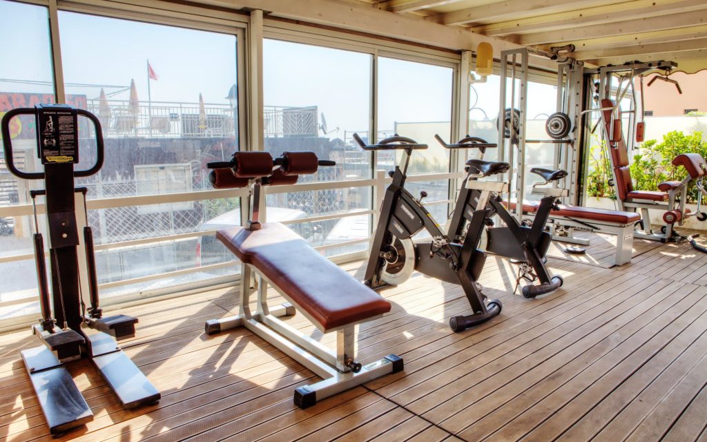 palestra interna con parete a vetri, pavimento parquet e macchine per il body building