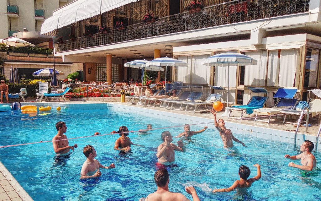 piscina dell'hotel con bambini e ragazzi che si sfidano a pallavolo