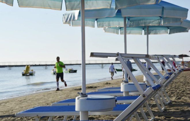 persone passeggiano e corrono sul bagnoasciuga